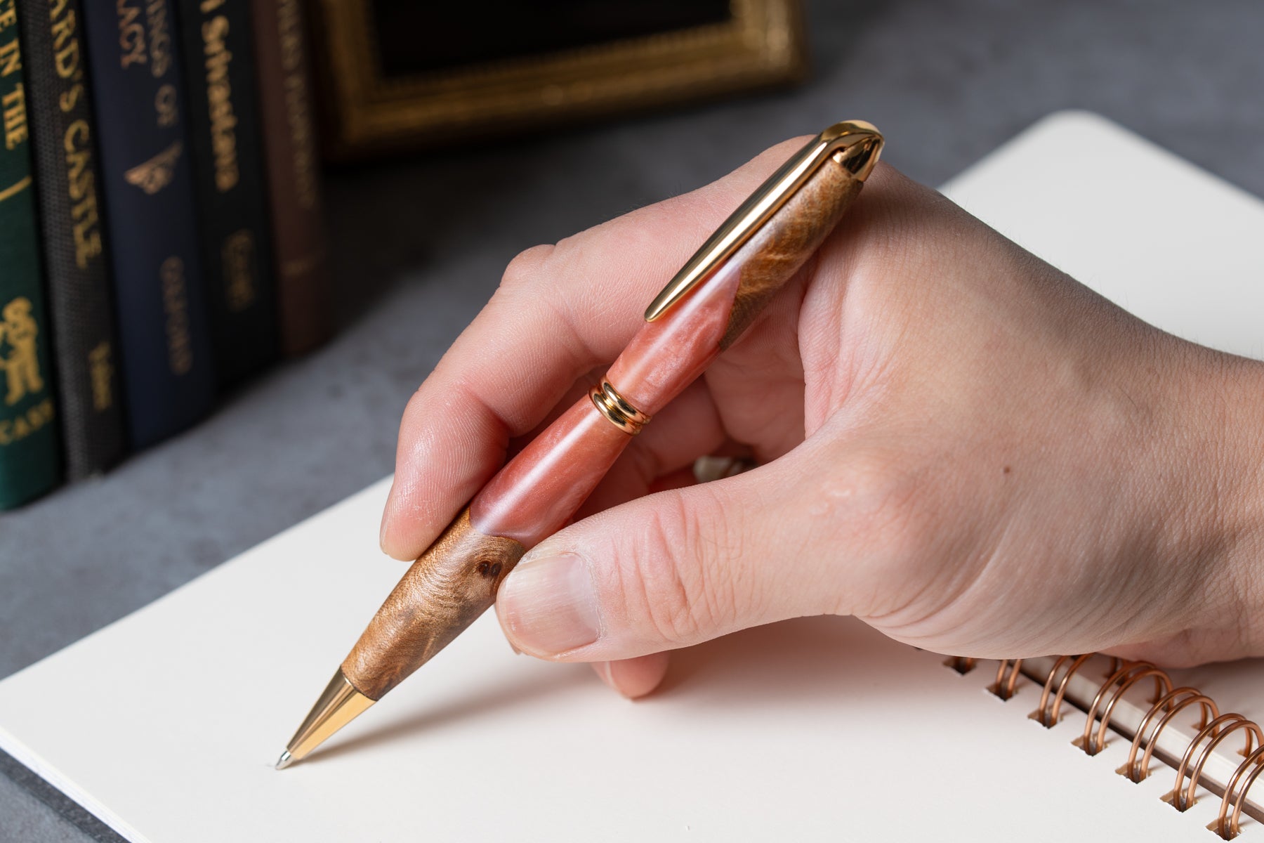 ピンクの瘤杢とレジンの木軸ボールペンでノートに書く手元